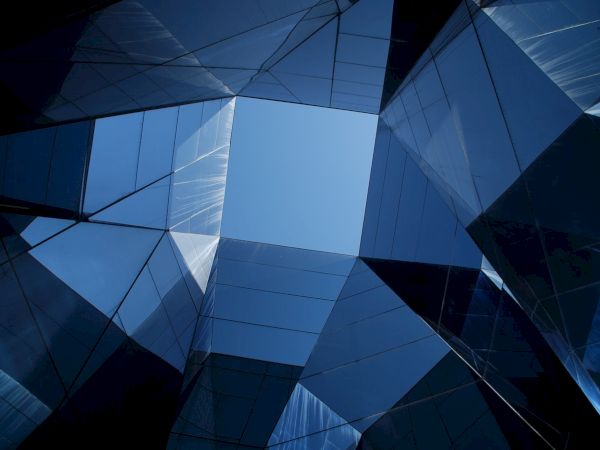 A view of the sky framed by geometrically arranged reflective glass surfaces, creating an abstract, modern architectural design.
